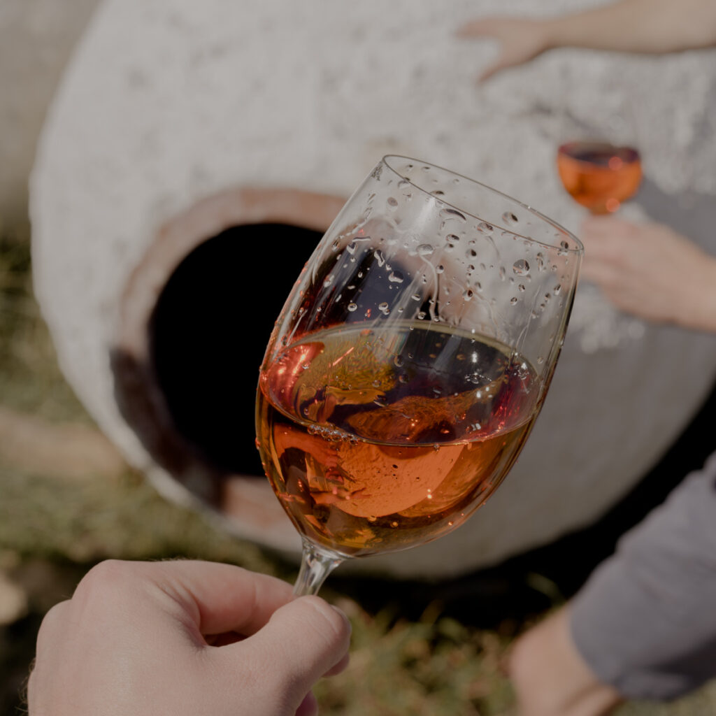 Ein Glas Orange Wein vor einer Amphore